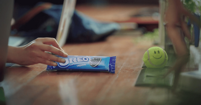 A hand holding a package of Oreo cookies on a desk