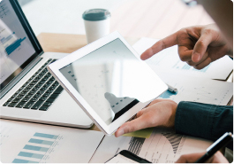 hands holding a tablet in front of a laptop