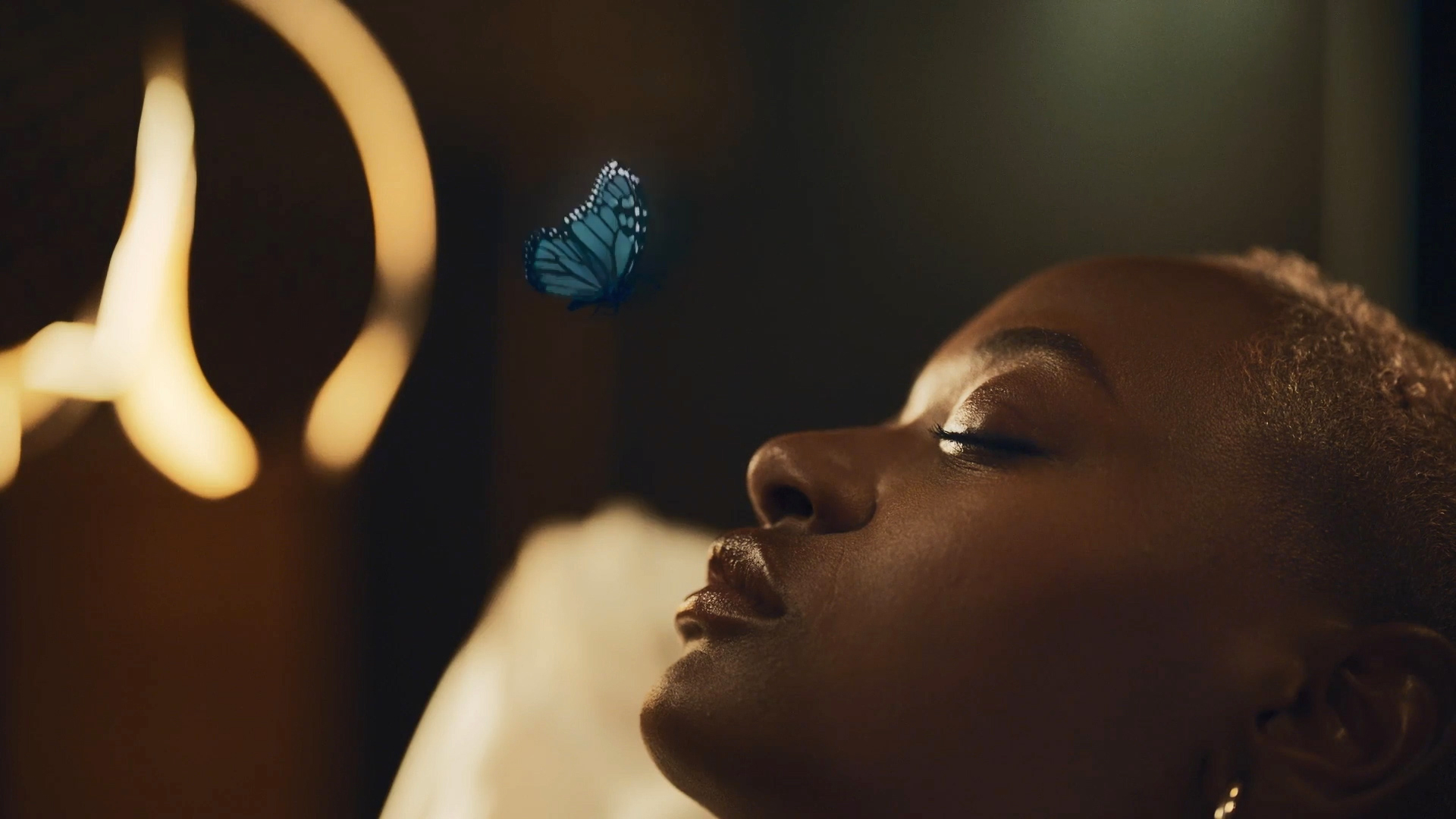 A woman lying down with a blue butterfly over her nose