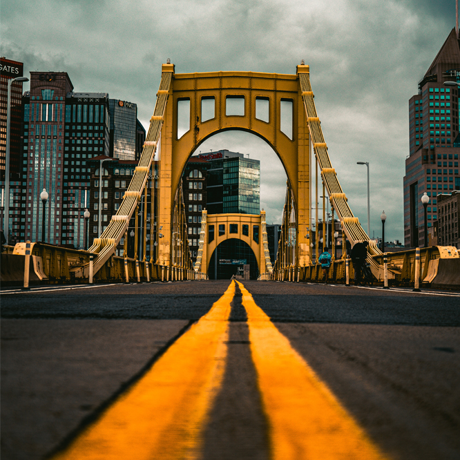 A yellow bridge leading into Downtown Pittsburgh