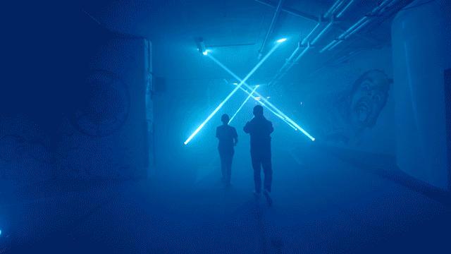 a smokey room with lasers and people running throughout
