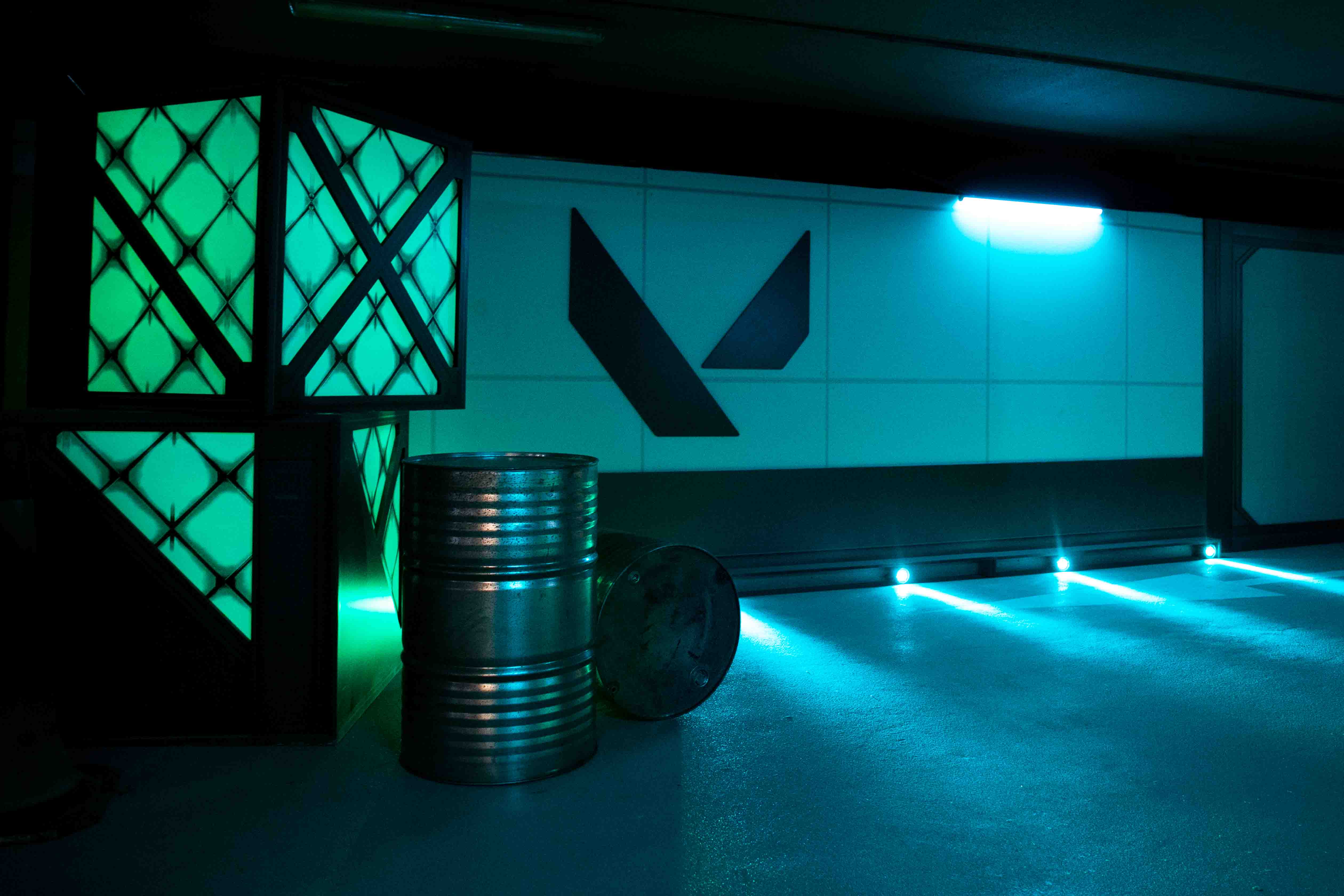 A Valorant logo on a wall with blue lights shining around it