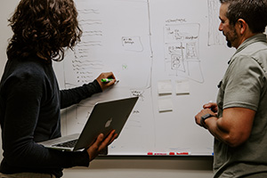 Two people working at a whiteboard together