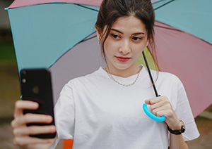A girl taking a selfie under an umbrella