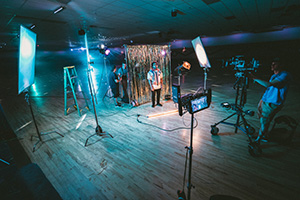A production in process with lights, camera equipment, and actors