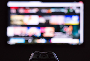 A tv and remote showing commercials