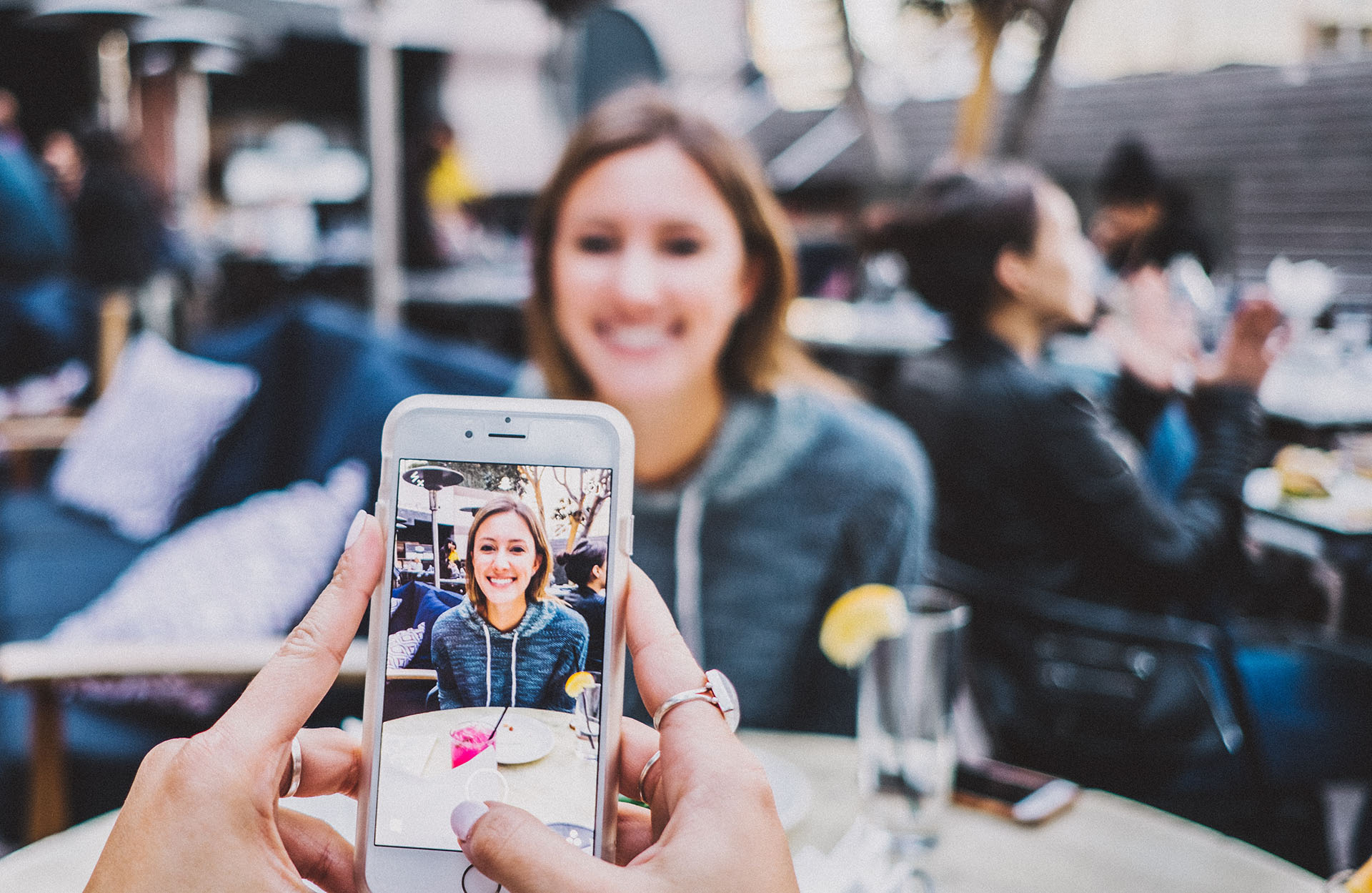 A phone taking a picture of another person at a table
