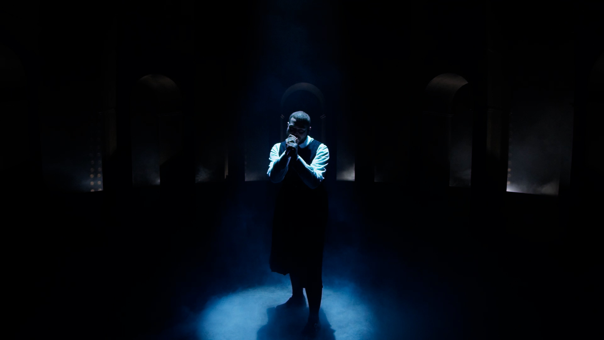 Post malone on stage singing in the dark lit by a blue strobe