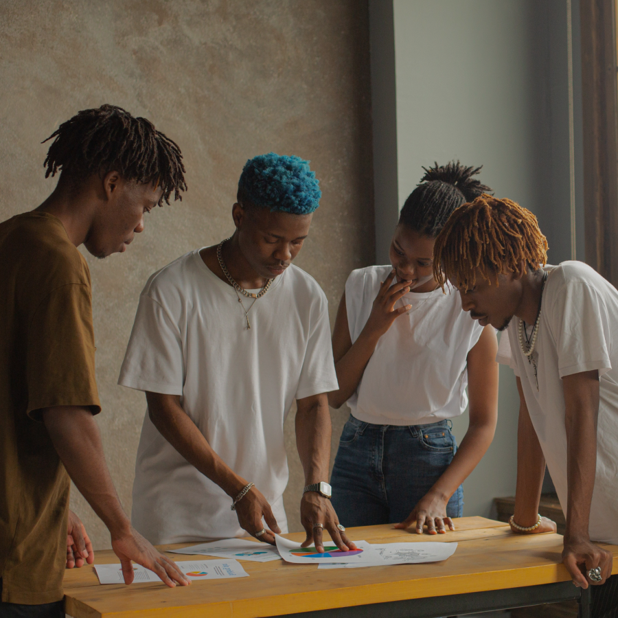 group o people standing around a table and looking at paper on the table