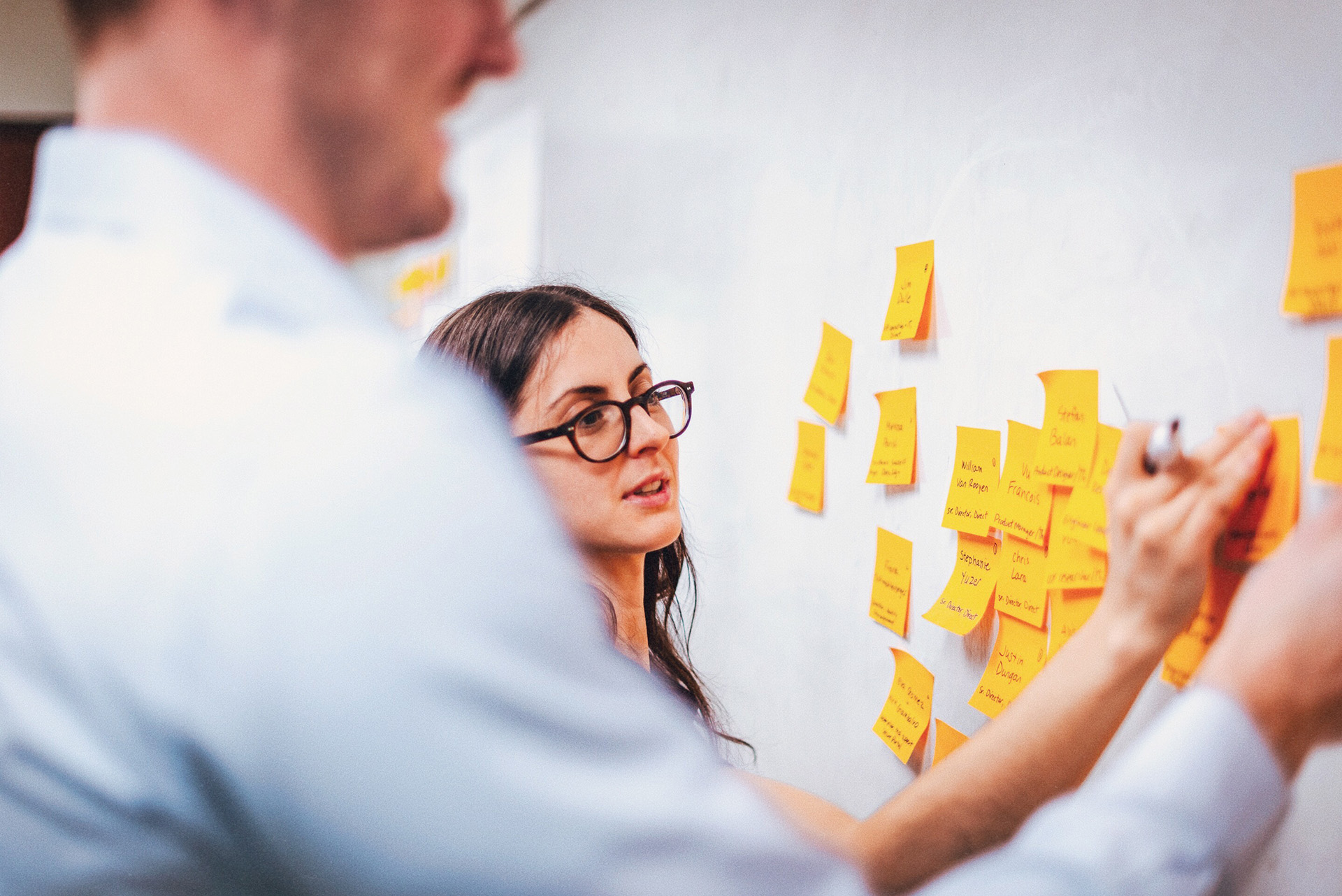 Employees working together at a whiteboard with post it notes