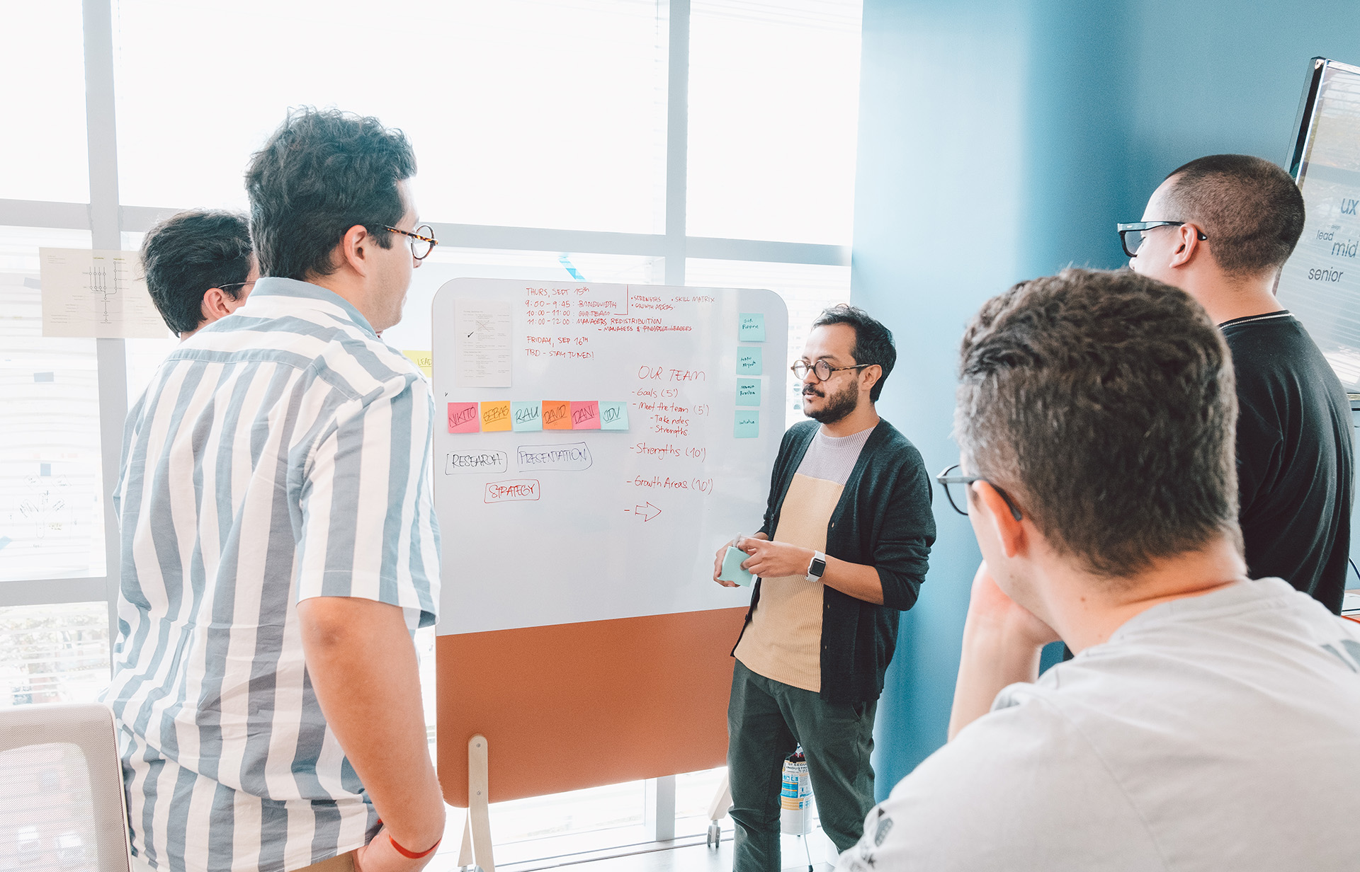 tech workers collaborate together by a white board