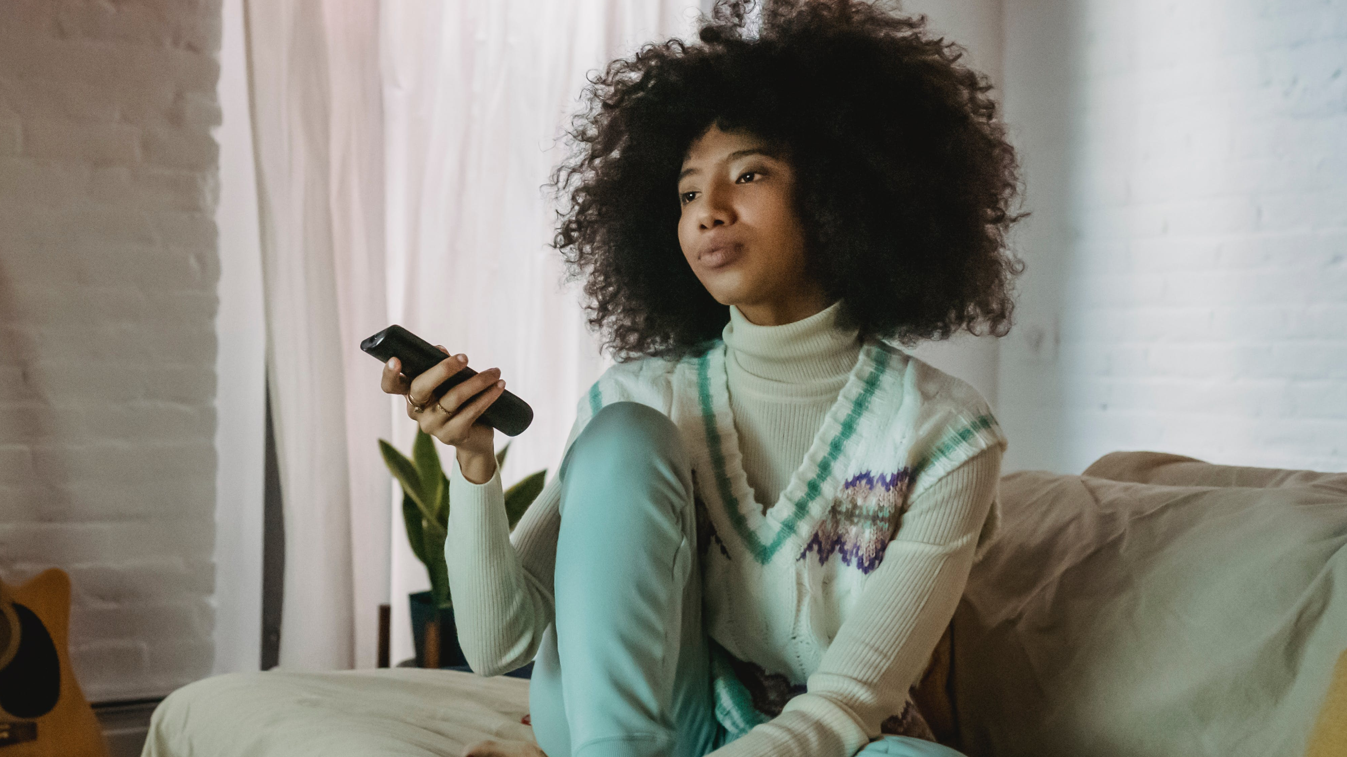 Woman holding a remote to watch TV
