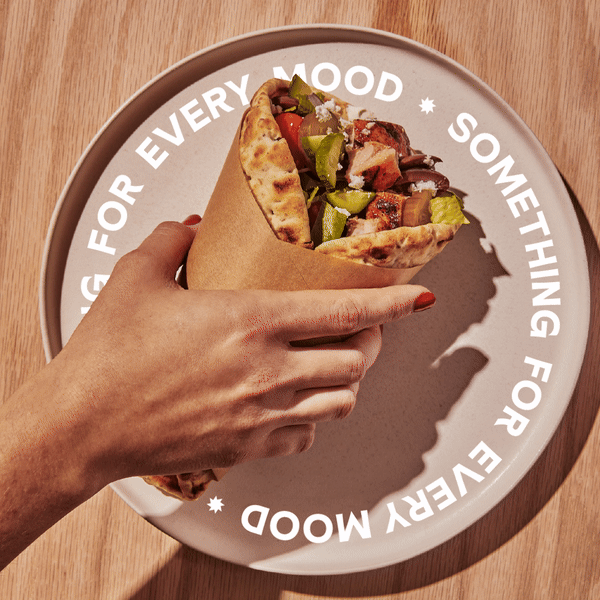 Animated image of a wrap from CAVA held by a hand over a plate