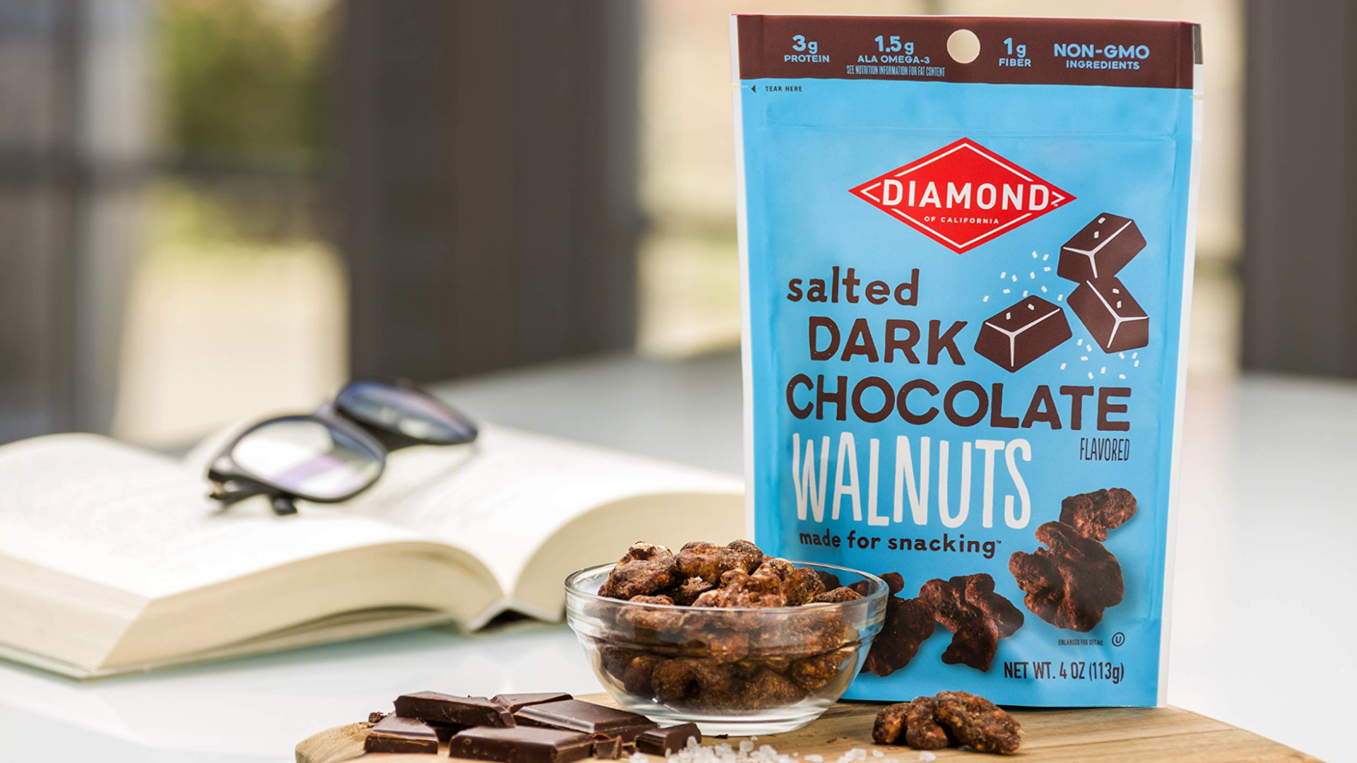 Diamond Foods chocolates in a blue bag on a table with a book and a cutting board