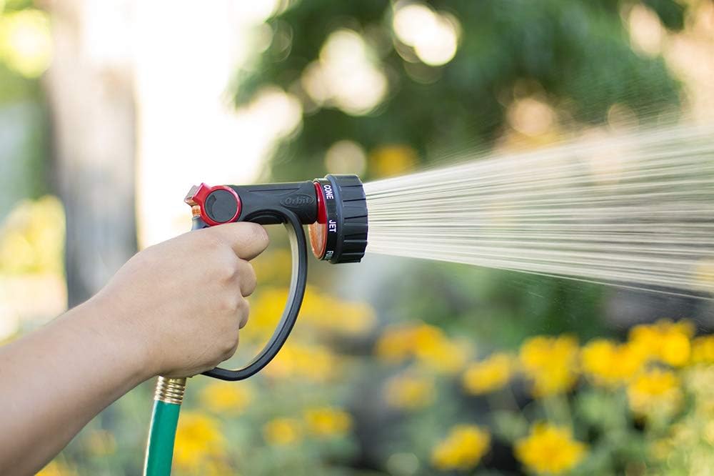 An Orbit hose being sprayed in a garden of yellow flowers