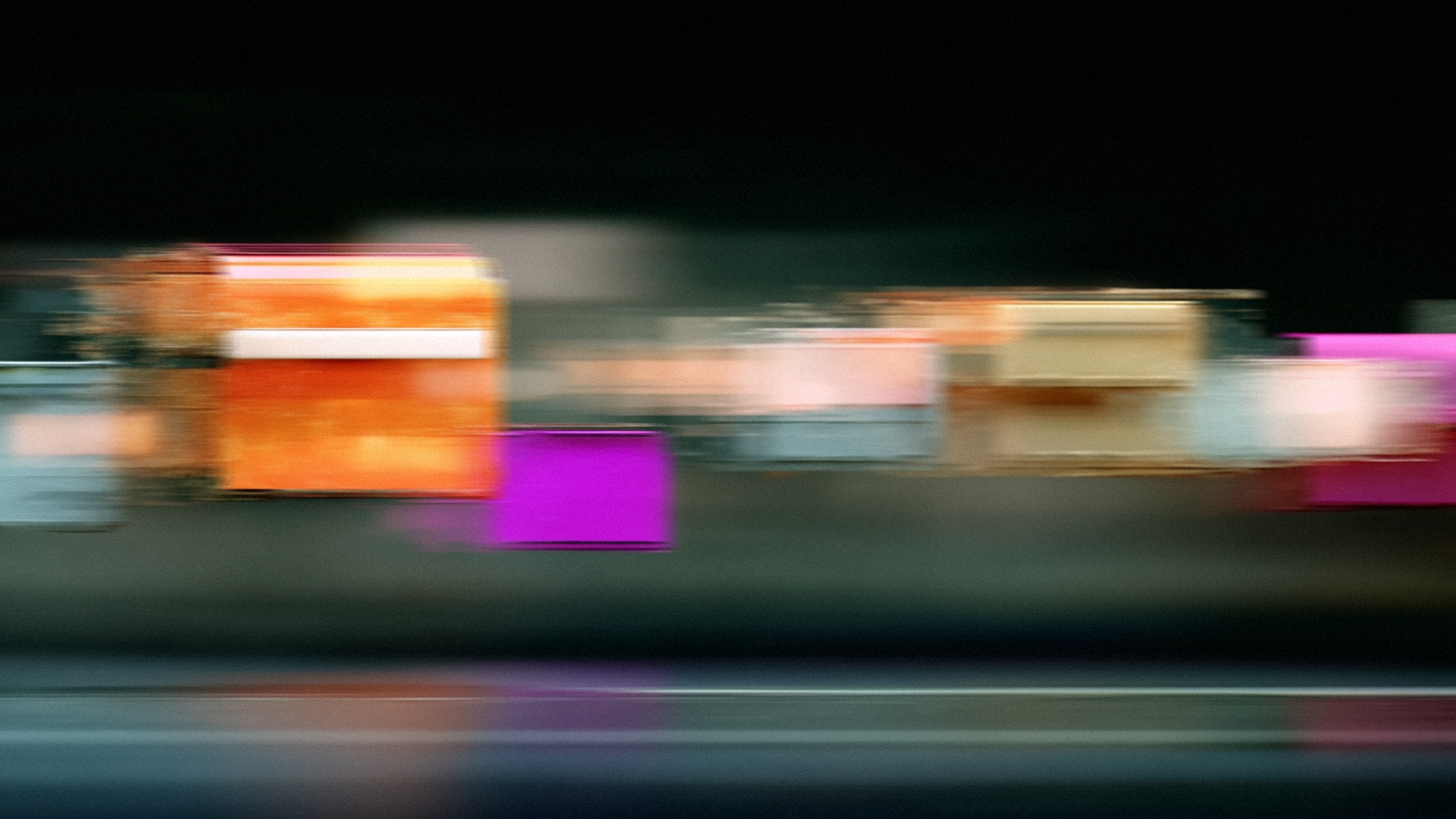 An abstract photograph of colorful rectangular shapes streaked horizontally with motion blur against a dark background.