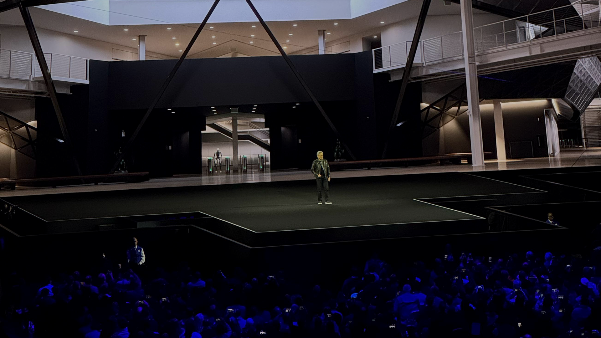 A lone speaker, dressed casually, commands a dark, futuristic stage during a major NVIDIA technology event, emphasizing the innovative live production and digital storytelling created by Monks.