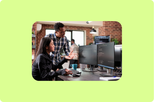 Employees working together around a desk looking at a computer