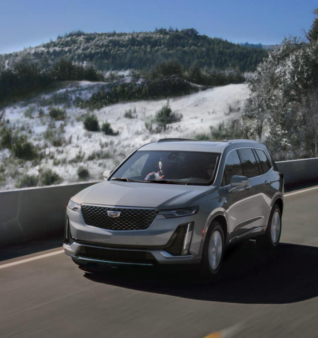 Cadillac XT5 driving on a highway in the mountains covered in snow