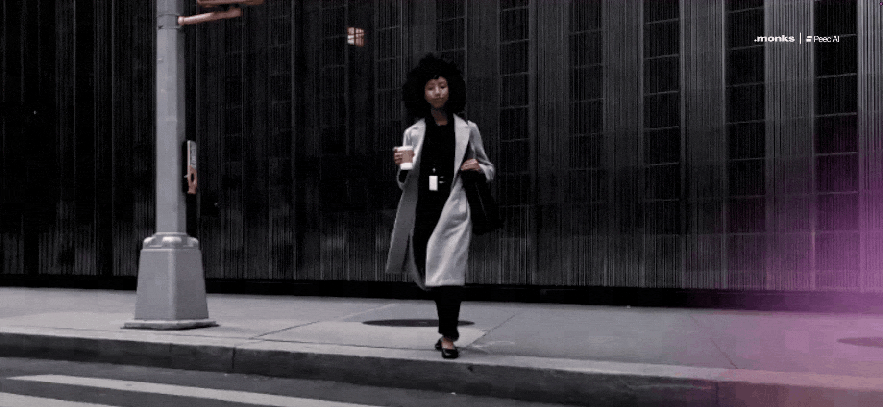 Woman in a light coat holding a coffee cup crosses a city street at a pedestrian crossing