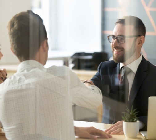 Three people in an office with computers discussing financials