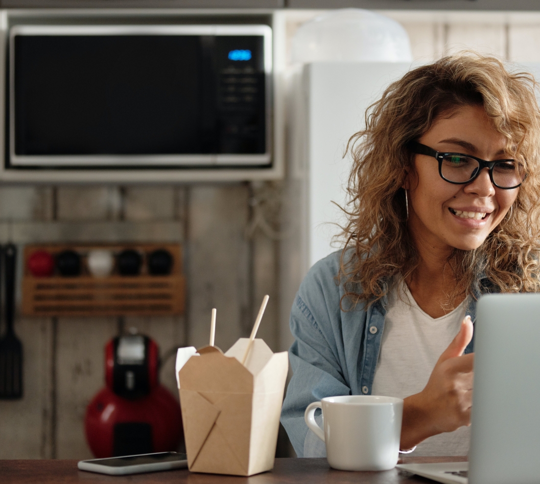 mulher no computador e comendo enquanto fala em chamada de vídeo