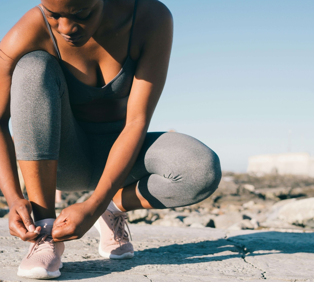 Mulher amarrando seus cadarços em uma paisagem