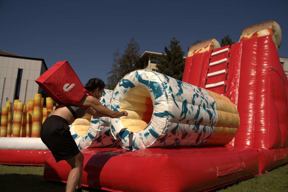 A person with a DoorDash delivery bag jumps through hoops in an obstacle course