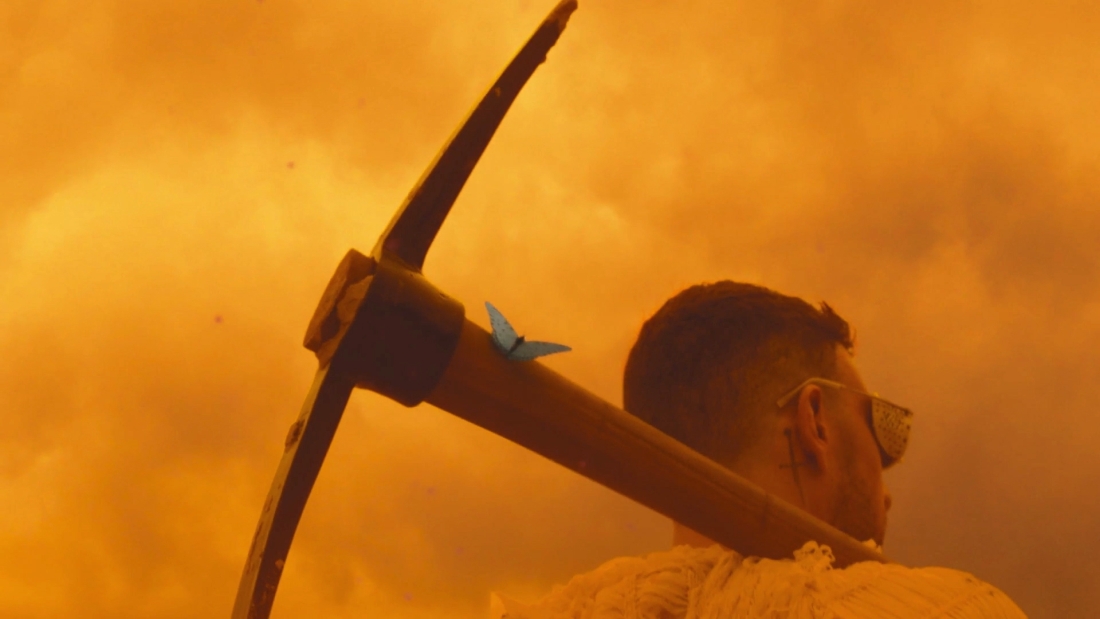 A person walking with a pick axe that has a butterfly on it