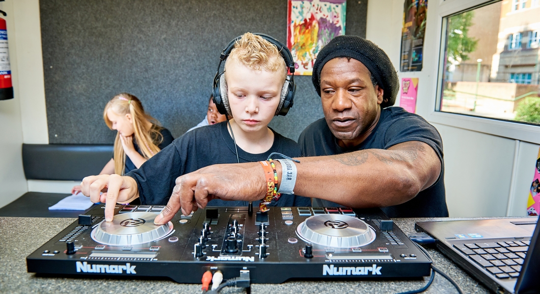A man showing a kid how to DJ