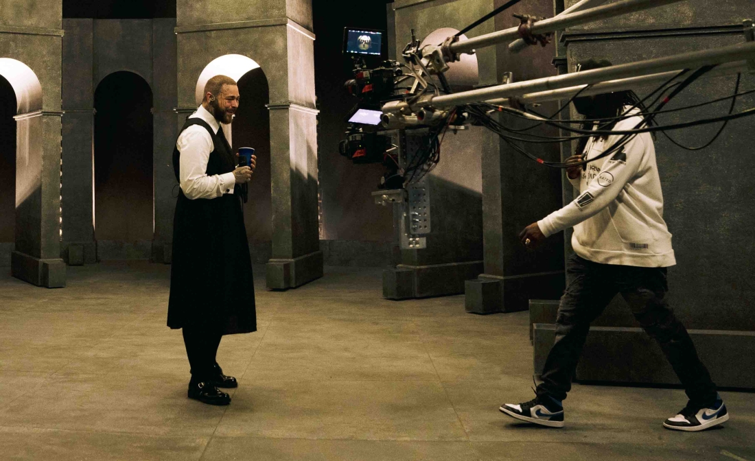 Post malone singing with a large camera hanging