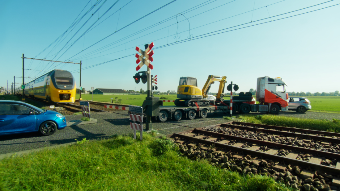 Situation of a dutch railway transition. A train is arriving but a truck did not clear the track yet.