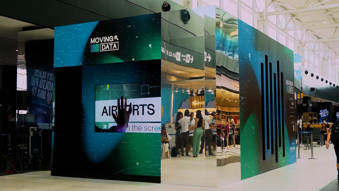 At an airport you see a large installation with mirror walls in blue and green.