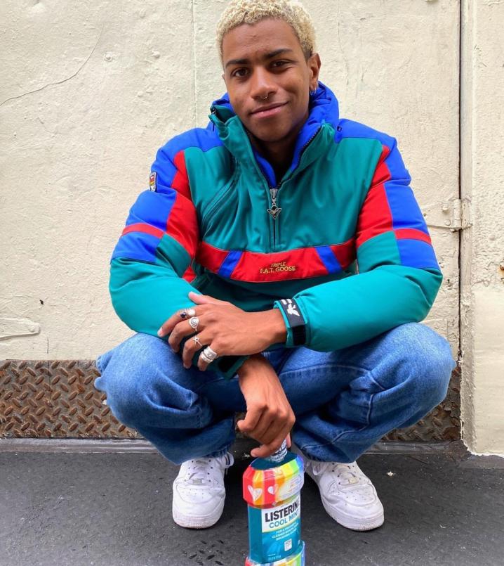 A person up against a wall holding Listerine  