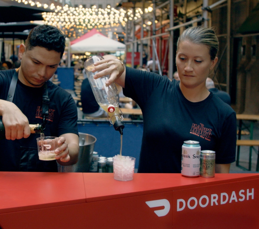 Two bartenders pour drinks at the DoorDash event