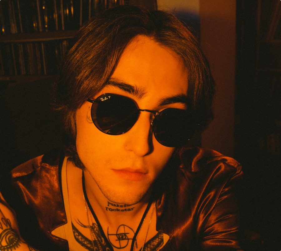 The image features a man wearing sunglasses and displaying various tattoos. He is shown in a close-up view, allowing for a detailed observation of his face and neck. The man's tattoos are particularly prominent, including those on his face and neck.  The focus of the image is on the man's face, with his sunglasses adding a stylish touch. The sunglasses themselves are not the main feature but contribute to his overall appearance. The man's lips are also shown in a close-up view, highlighting their details.