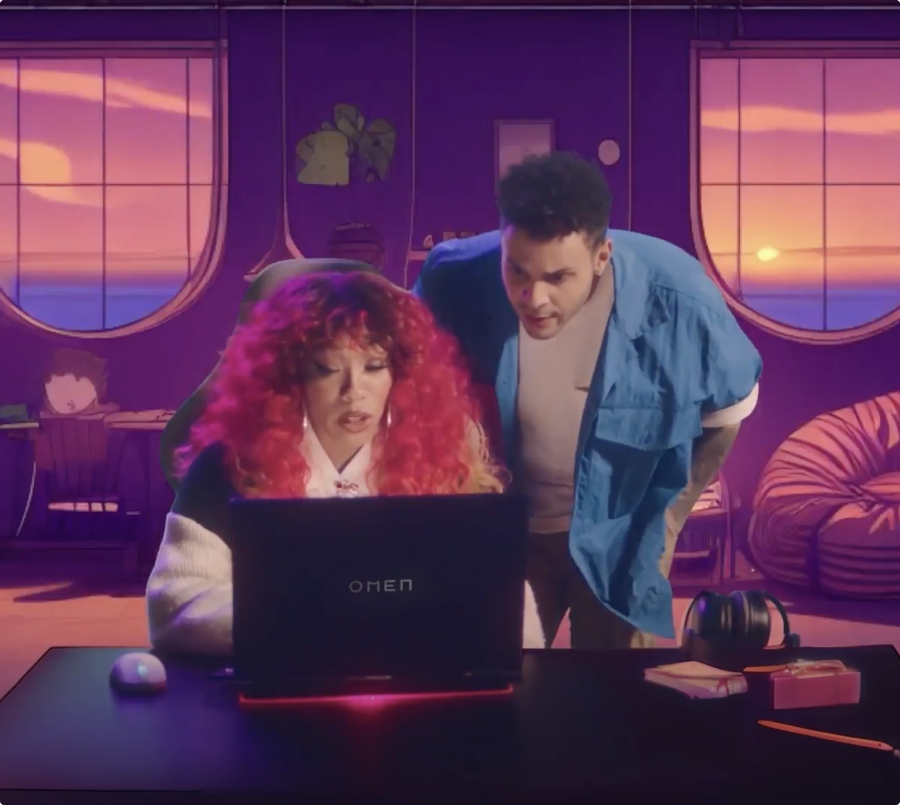 Women sitting on a couch looking at a laptop screen. A man looks at the same screen and is standing behind her.