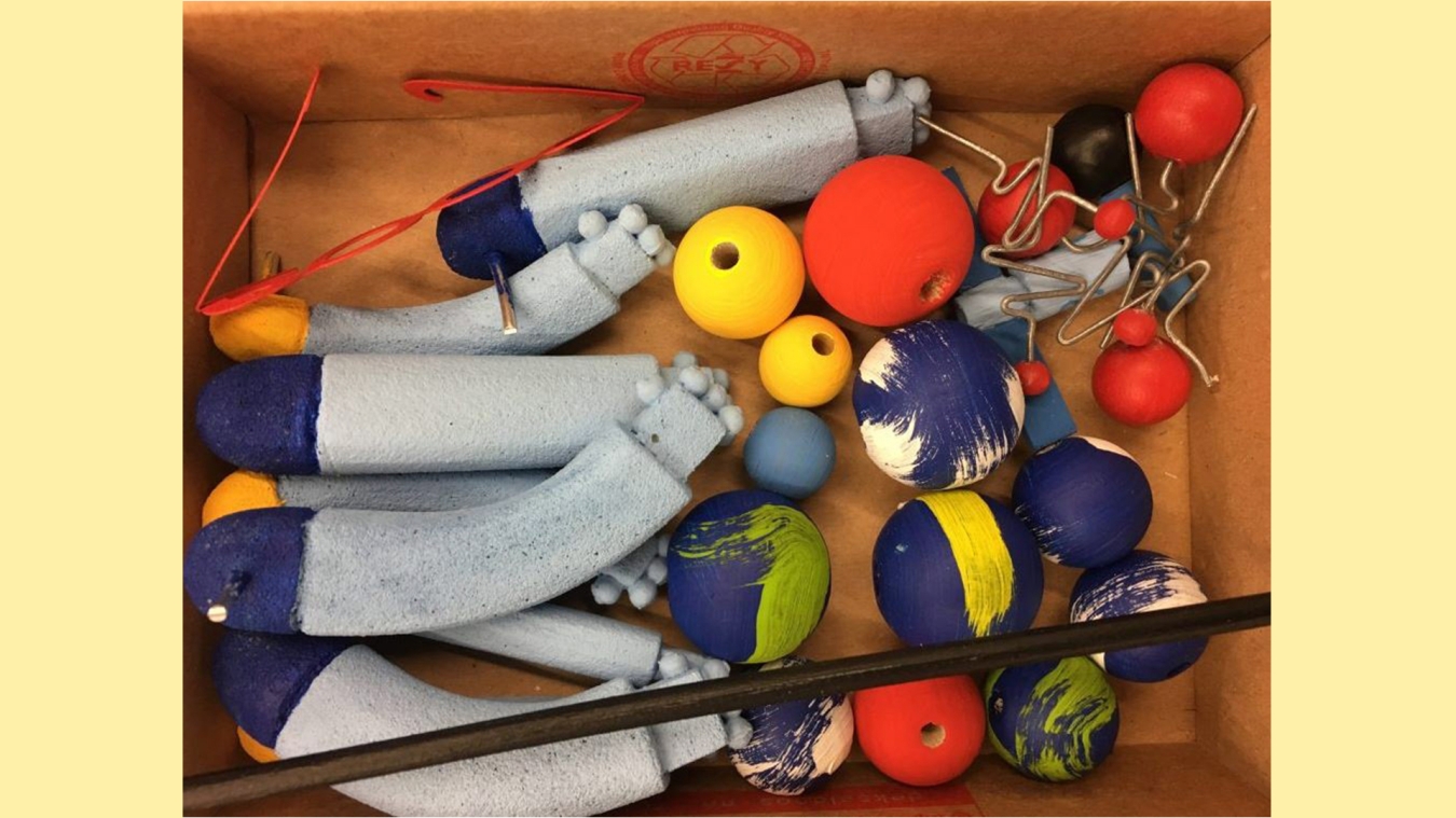 A box seen from above with all shapes. Different round balls in different colours and somethign that looks like arms.