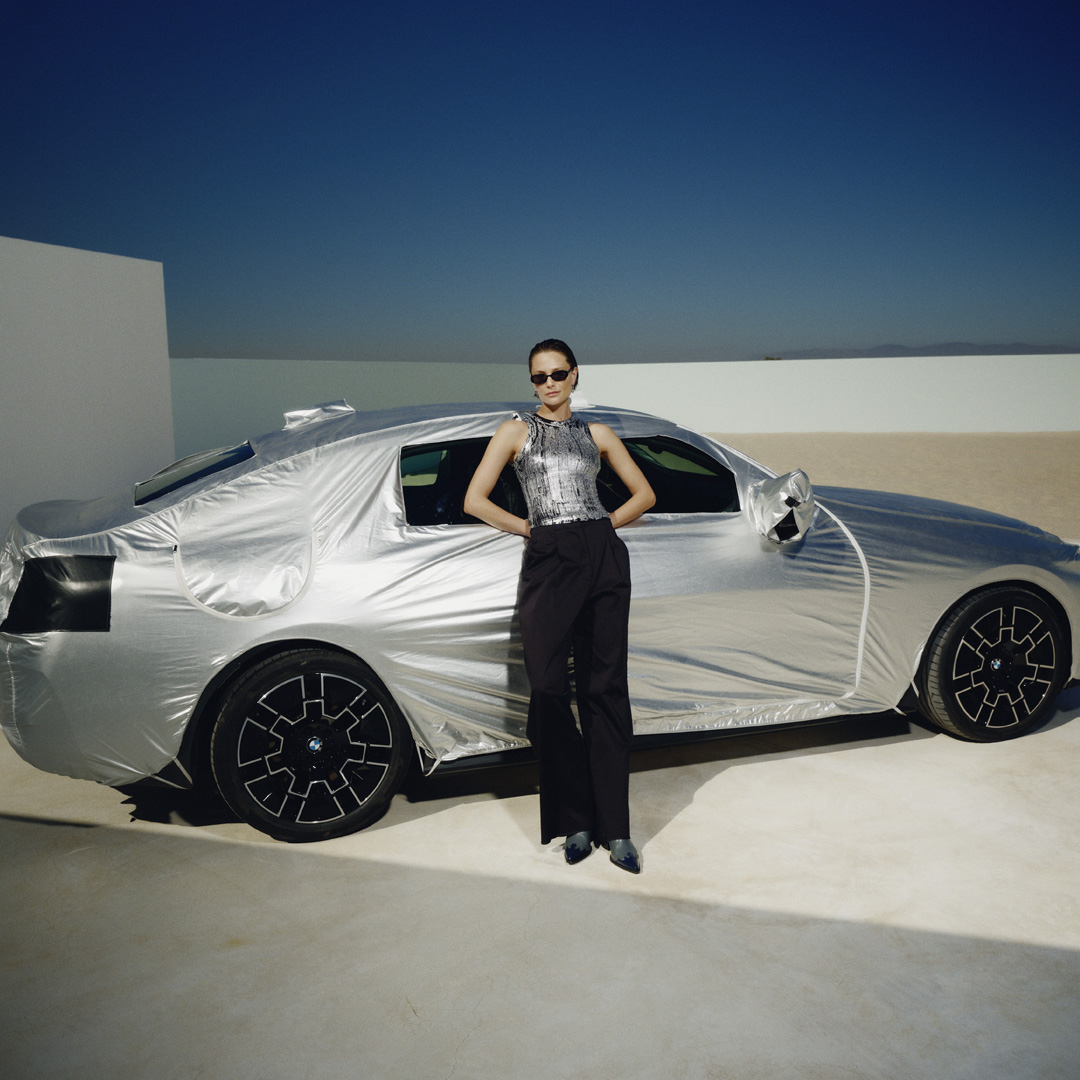 A woman standing in front of the bmw wrapped in silver