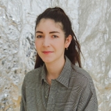 portrait of a woman with dark hair, wearing a collared shirt, against a shiny white background
