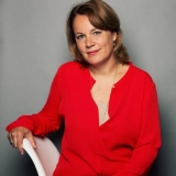 woman in a red dress sitting against a gray background