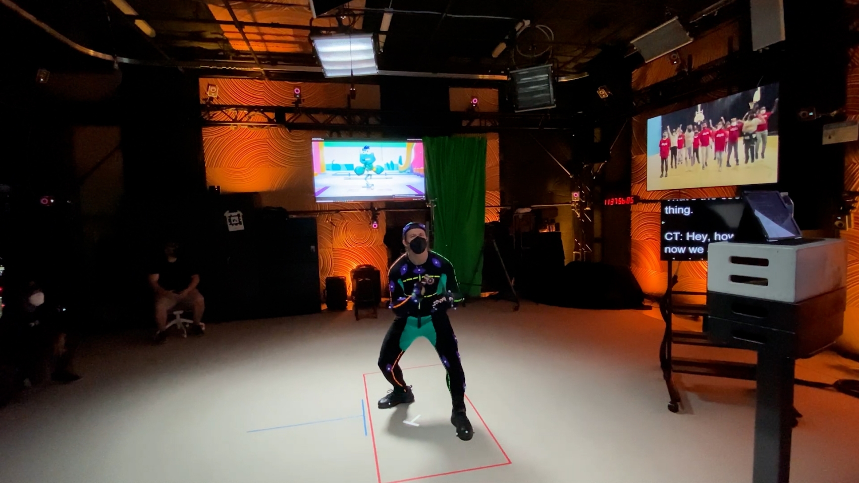 A stage with a person in a mocap suit being filmed