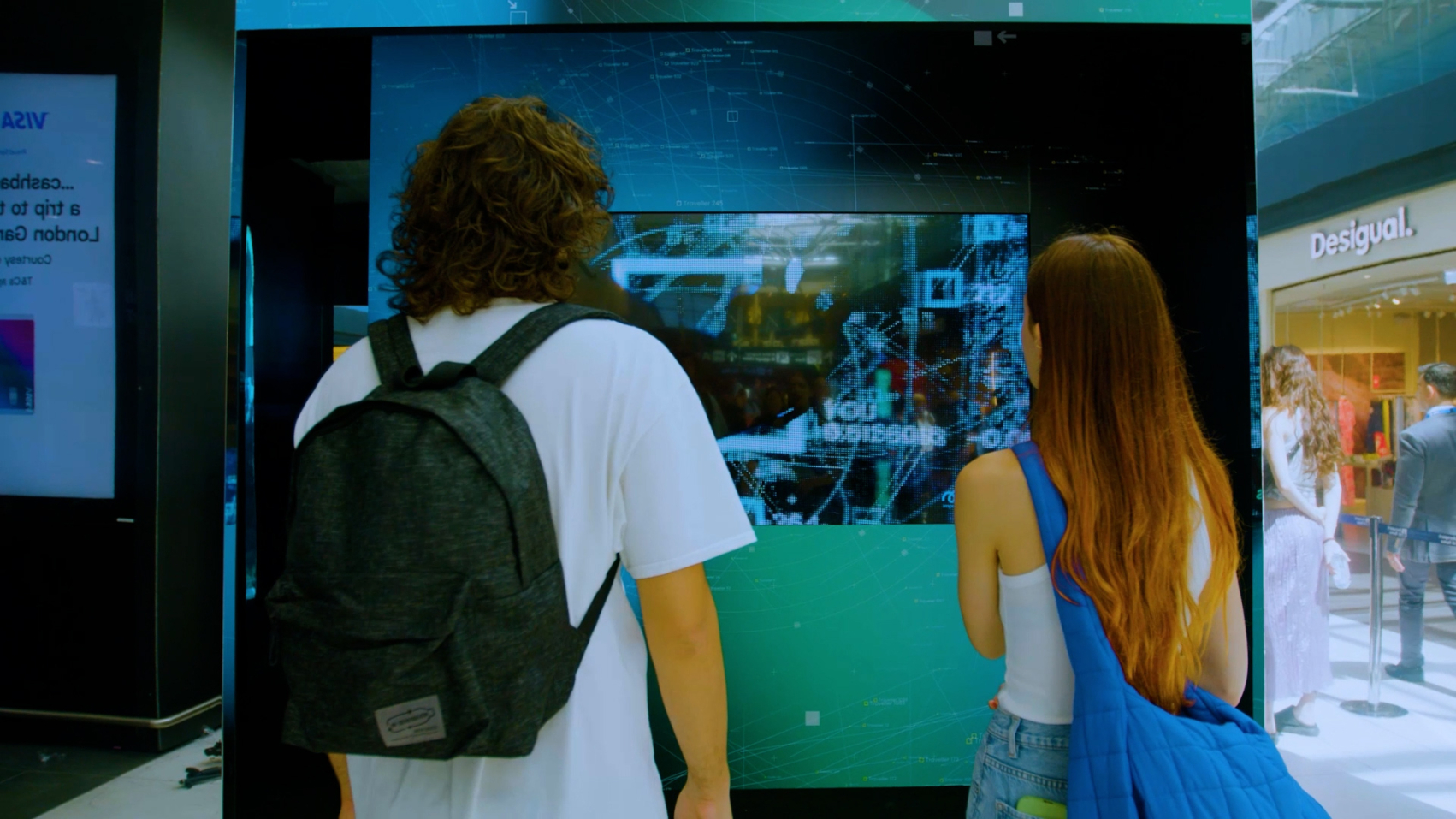 Two travellers seen from the back standing in front of the entrance of an airport installation.