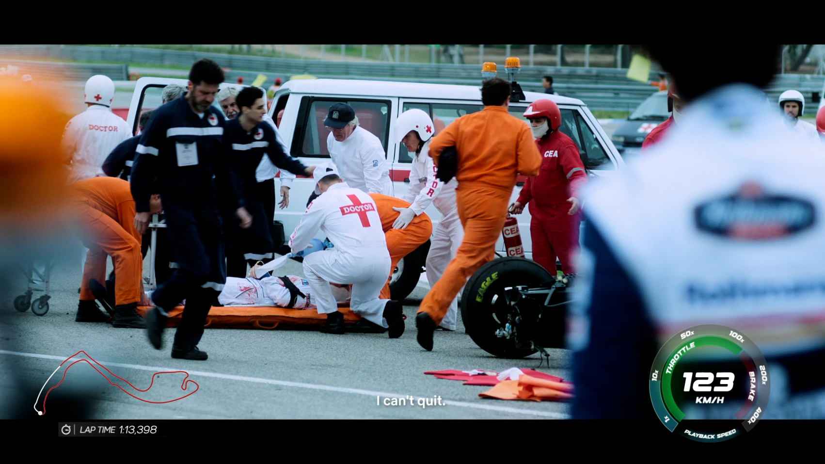The image depicts a chaotic scene on a racetrack, where a team of medical personnel is attending to an injured driver lying on a stretcher, while another driver expresses determination with the words "I can't quit" visible on the screen.