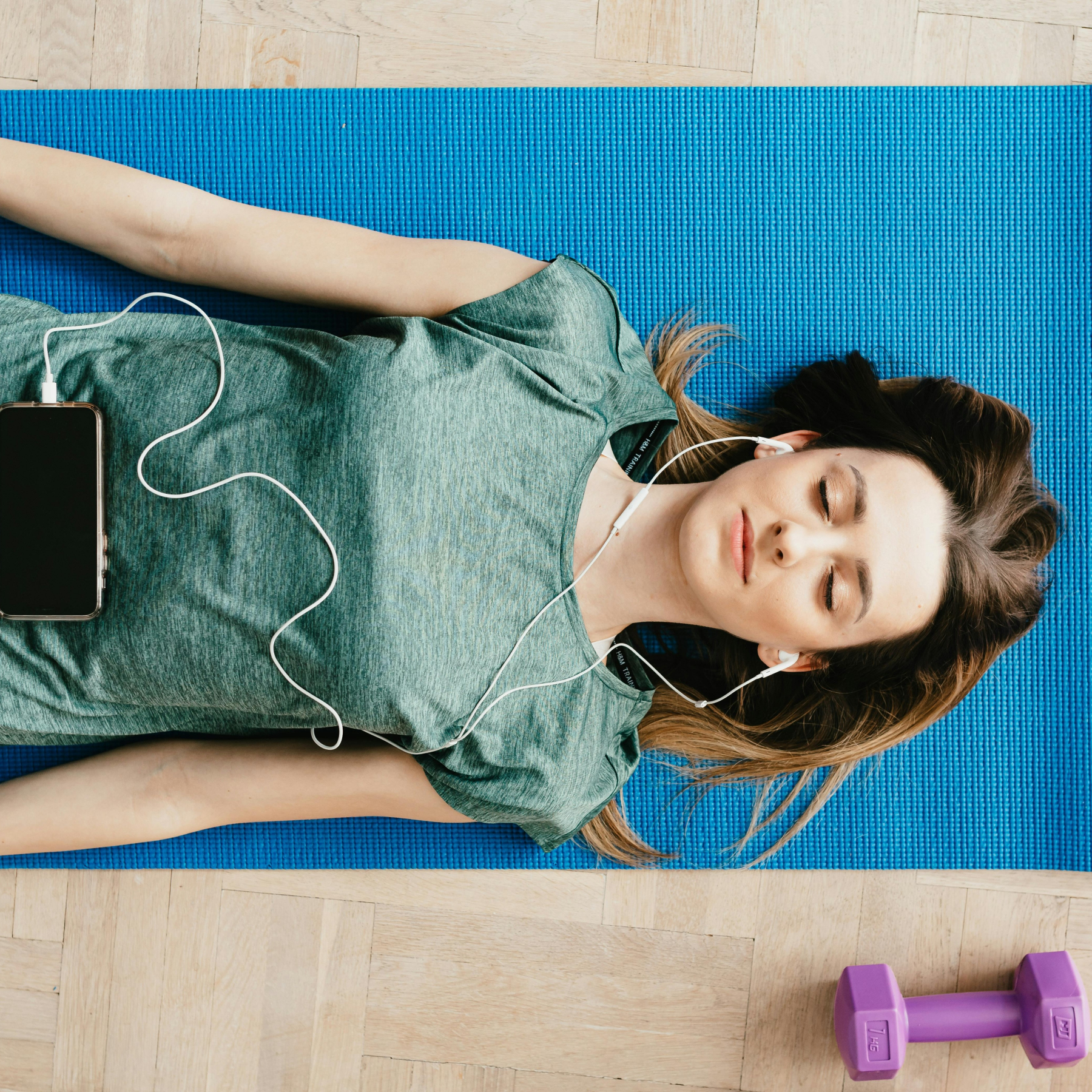 A woman laying on a yoga mat with headphones in