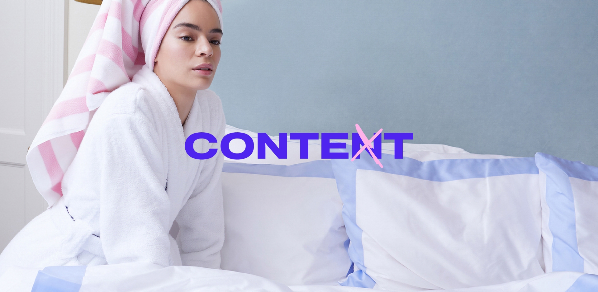 A woman sitting on a bed with a towel around her head