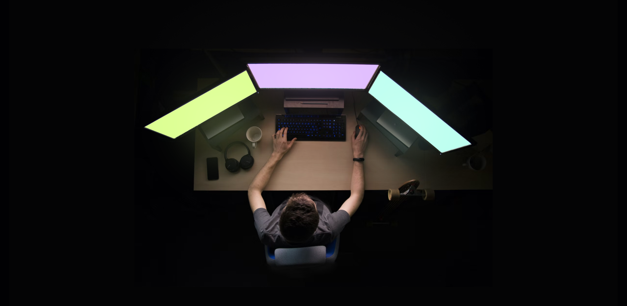 A person sitting at a desk with three monitors