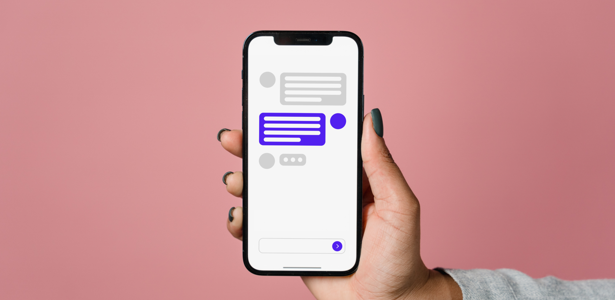 A hand holds a smartphone to the viewer. On the phone is a conversation between a user and a chatbot. The conversation isn't legible.
