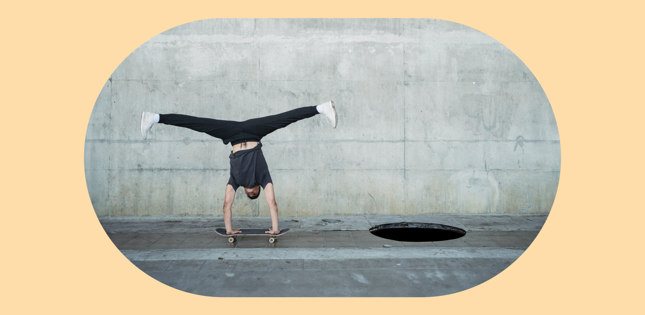 Photo of a man doing a handstand on a skateboard that is hurdling to a pitfall on the ground.