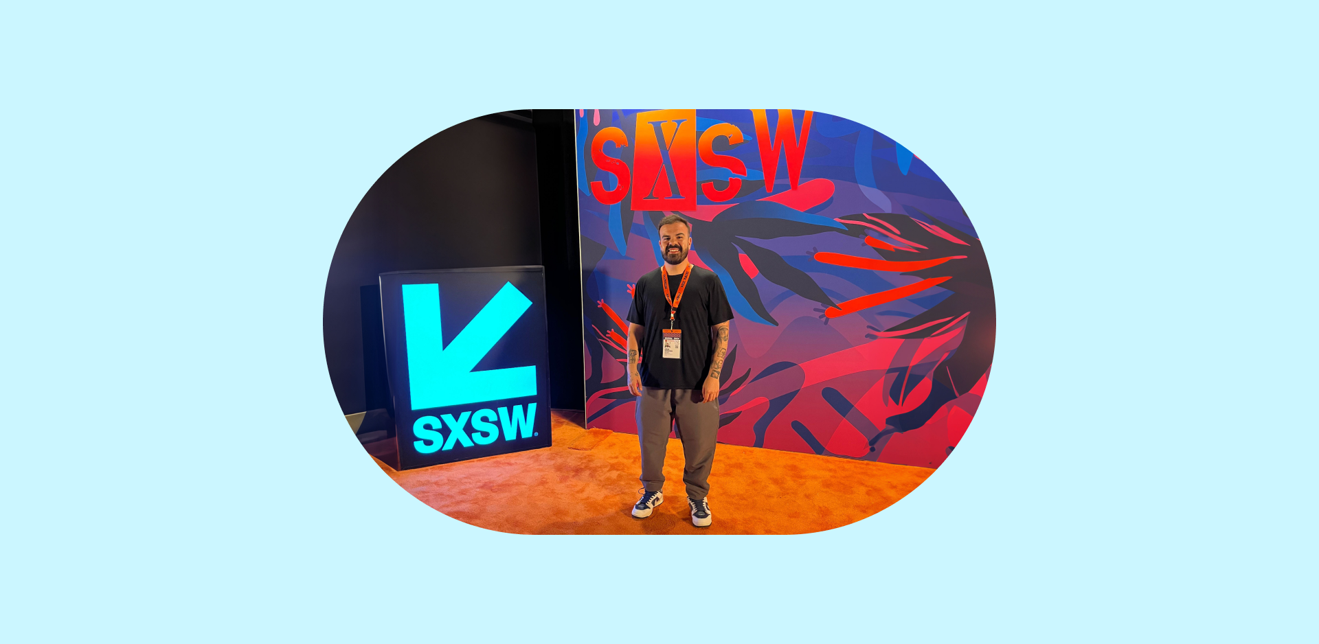 Foto de corpo inteiro de um homem com barba parado em frente ao logo do evento SXSW